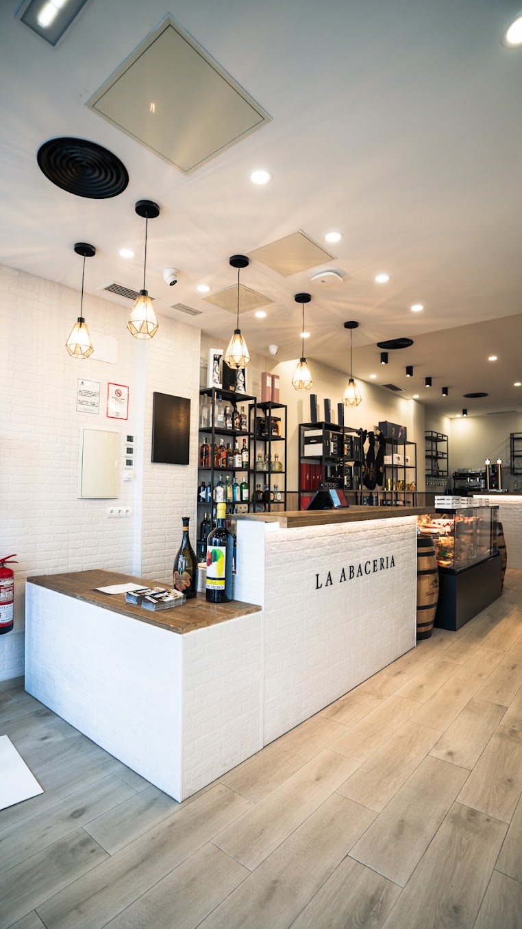 La barra de La Abacería, con vinos, vitrinas y lámparas cálidas